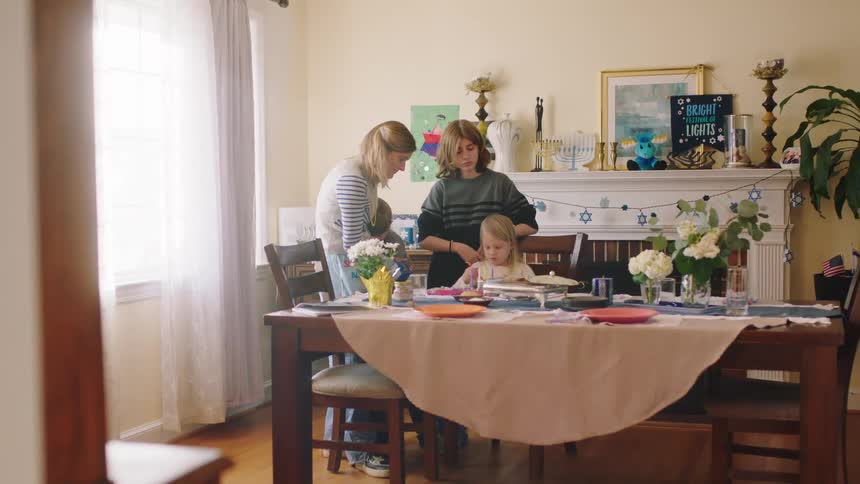 Family stands watching girl crafting at table set