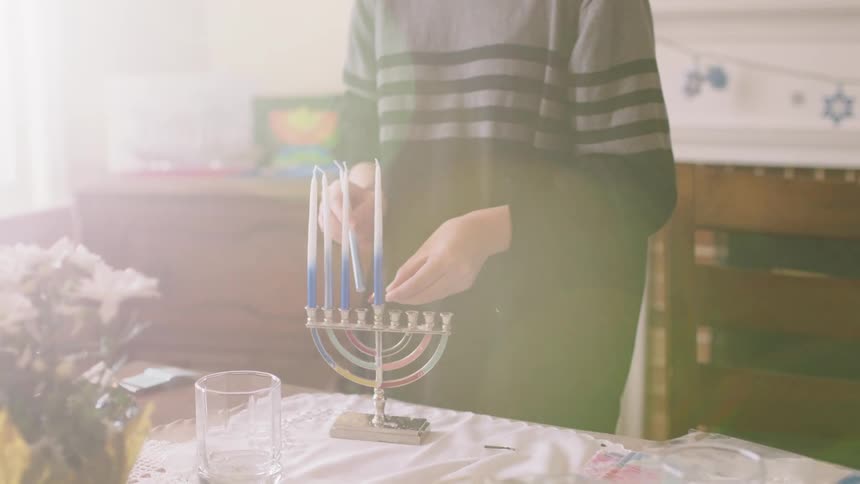 Mother and daughter burning the wax on the bottom of candles to put on a menorah