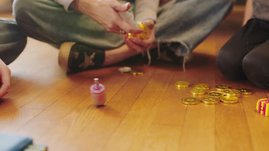 Mother and sons sitting on the floor at home playing with dreidels on hanukkah