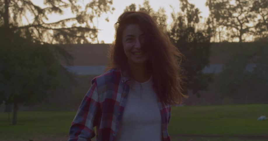 A woman smiles into the camera while standing in a field outdoors