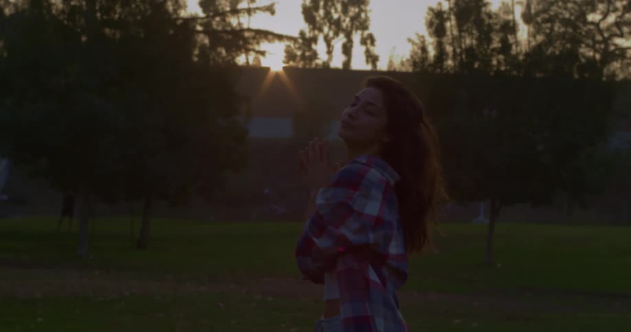 Woman standing in park shakes her hair then poses