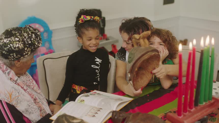 Family sitting around a happy girl in front of a birthday cake at home