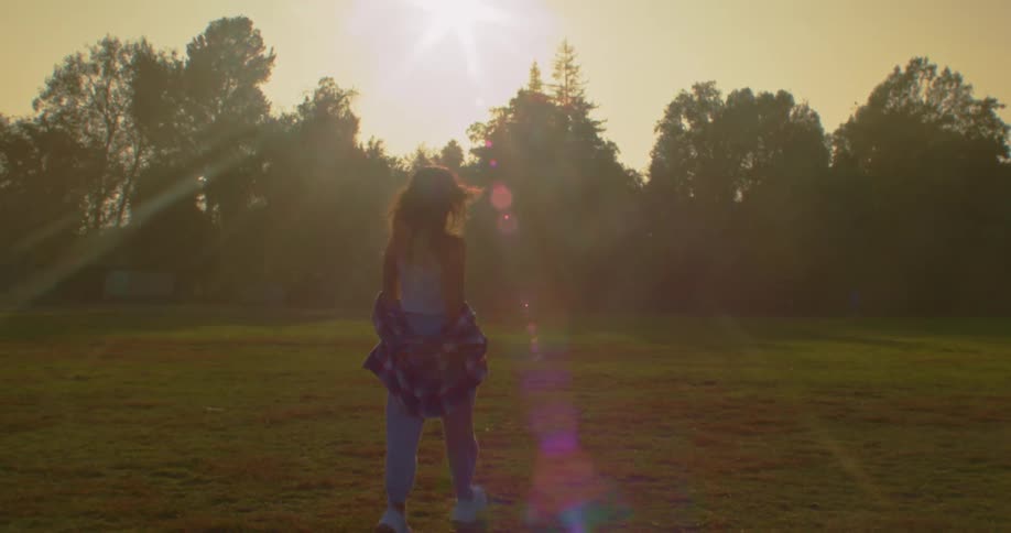Woman walks across mowed lawn as sun shines from red tinted sky