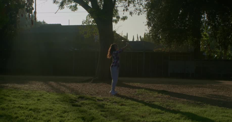 A woman spins around her yard while holding up her phone