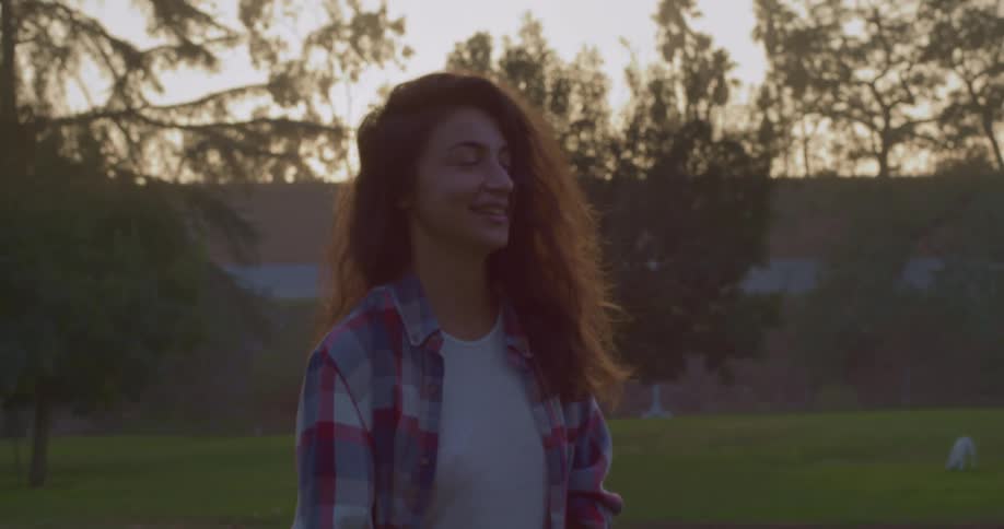 Woman stands talking as pet plays on ground bordering buildings in background
