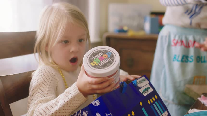 A girl screams out and shows off her birthday present while opening gifts