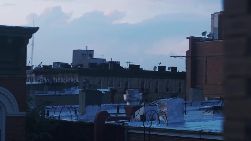 A layer of snow covers the rooftops of city apartment buildings