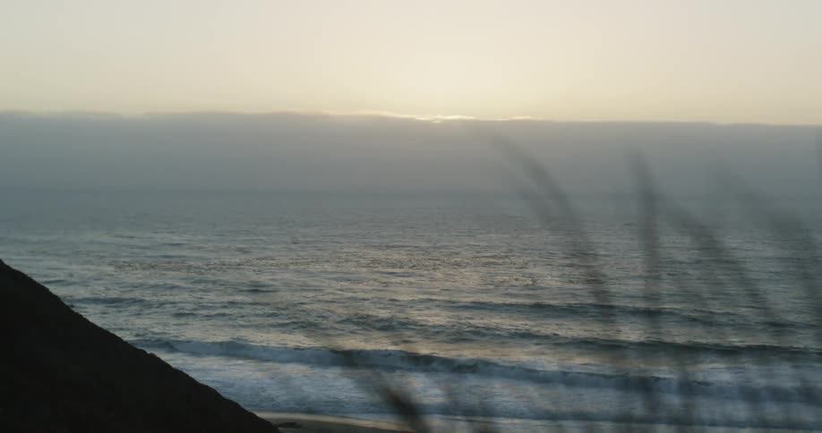 Sunlight gleams on the horizon as waves roll onto beach