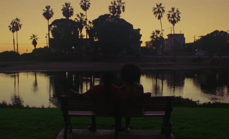A couple sit on the bench by the water