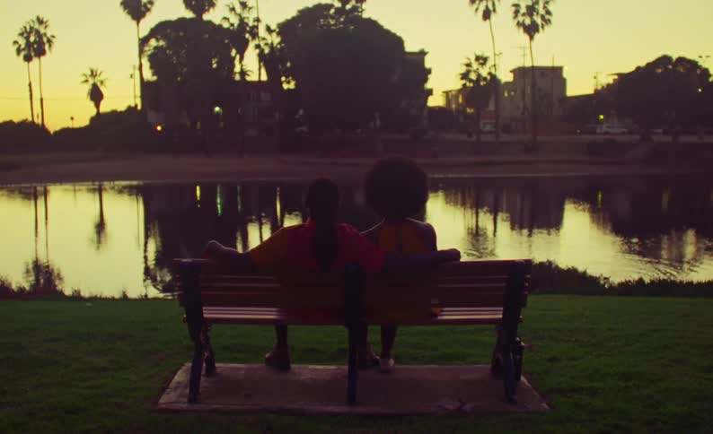 Two people sit on a bench in the park