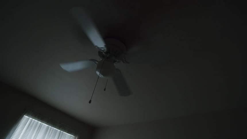 Ceiling fan spinning in a darkened room at mid day