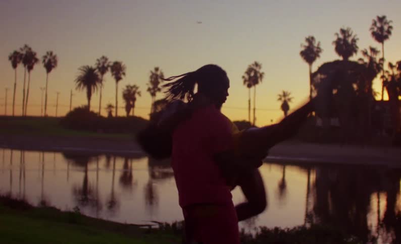 A man and woman dance together outside beside a large pond