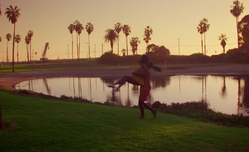 A man picks up a woman from behind and spins her as they perform a choreographed dance