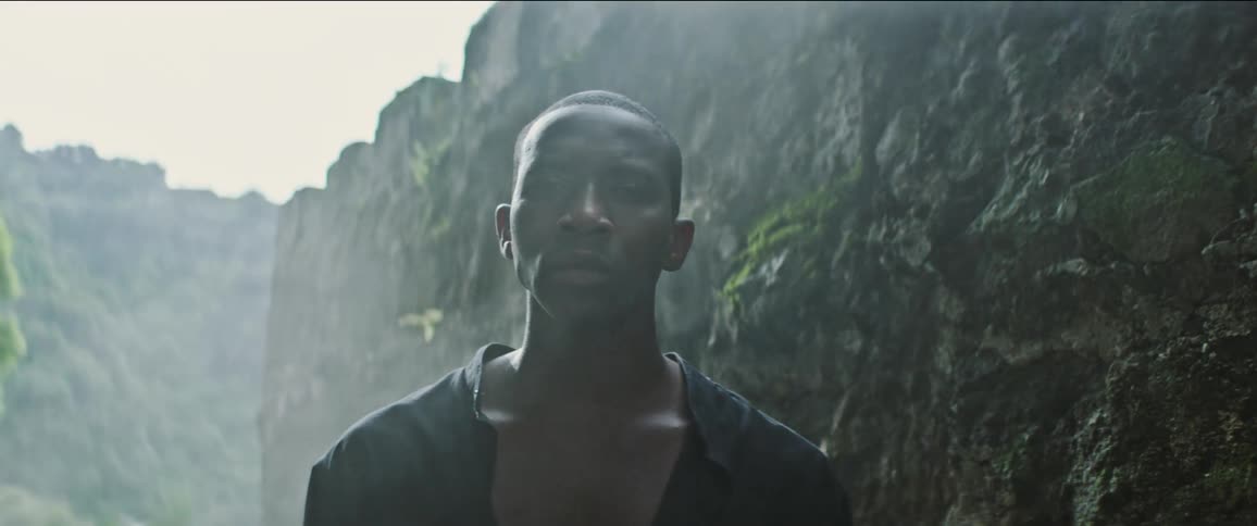 A man standing outdoors in front of rock