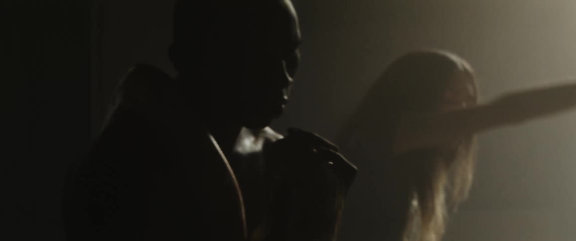 Silhouette of a young couple dancing inside a dimly lit room near a window