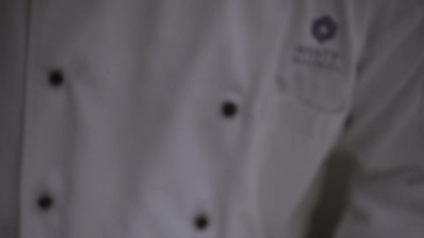 A chef is looking down as he cooks