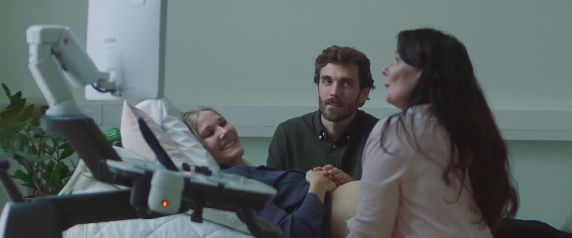 A man and woman grin as they watch an ultrasound of their baby