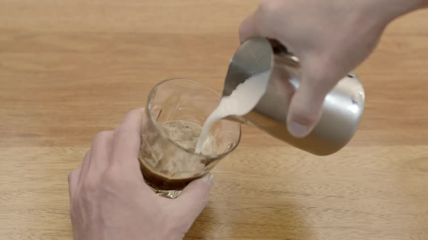 Cream is poured into a glass on a wooden table