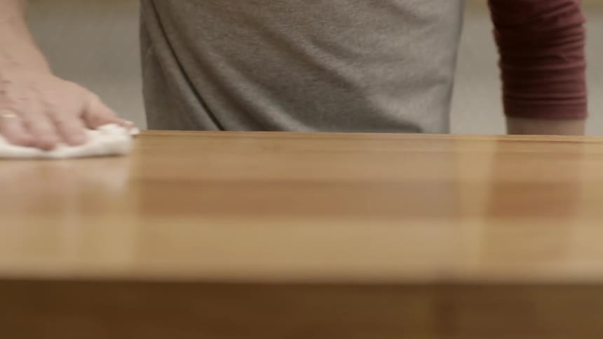 A person is cleaning a wooden table