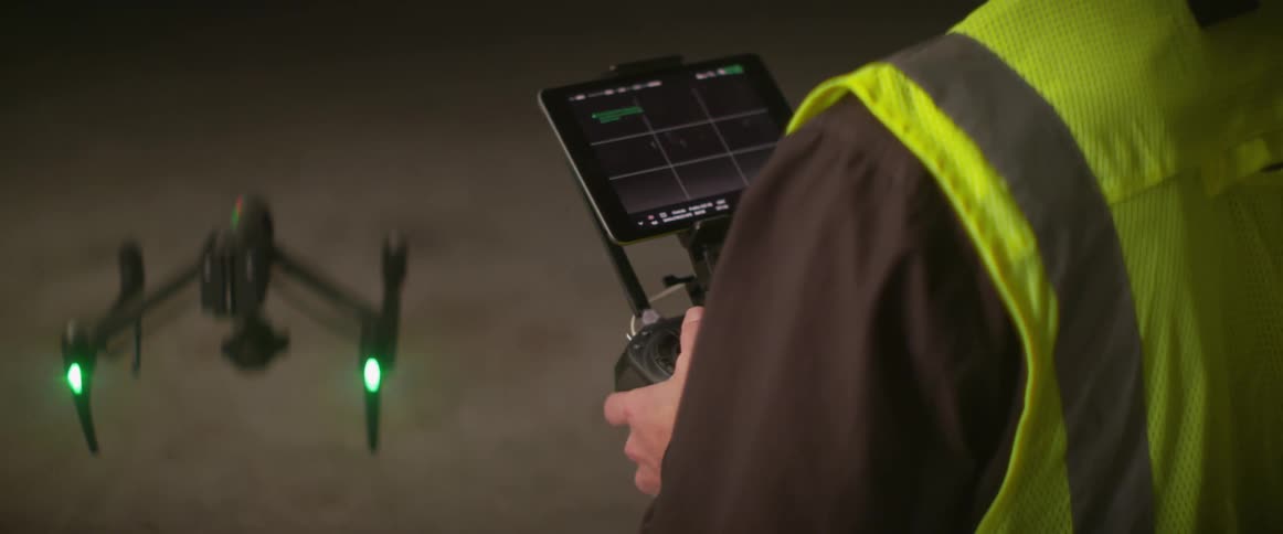 A man in a safety vest controls a drone