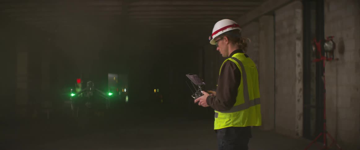 A construction worker flies a drone in the building