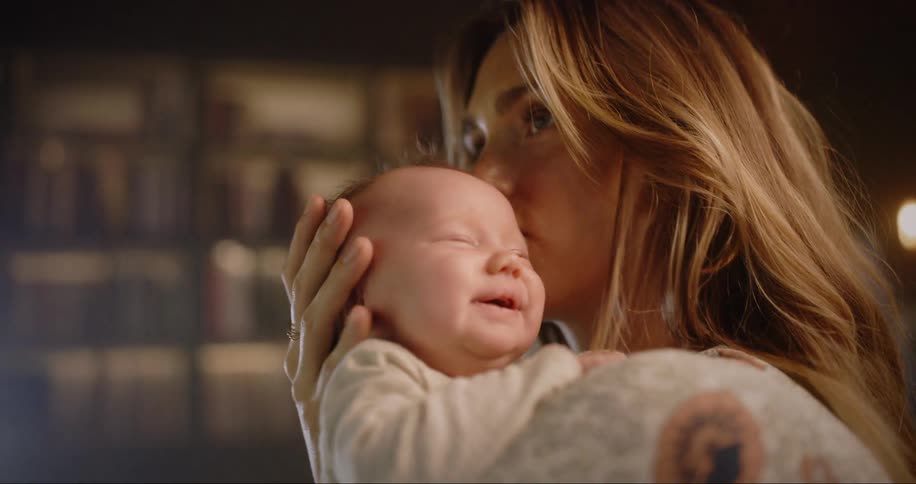 Mother holds and comforts child in room with floor to ceiling bookshelves