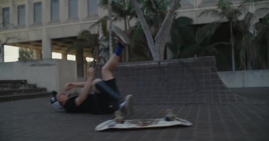Skateboarder with a prosthetic brace falls while attempting to perform a trick