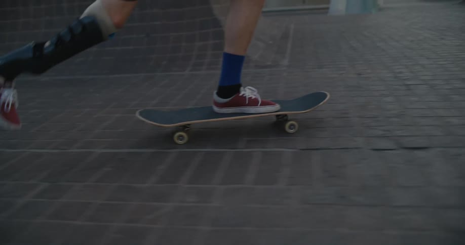 A man with an artificial leg attempts to do a trick while skateboarding through a city during the day