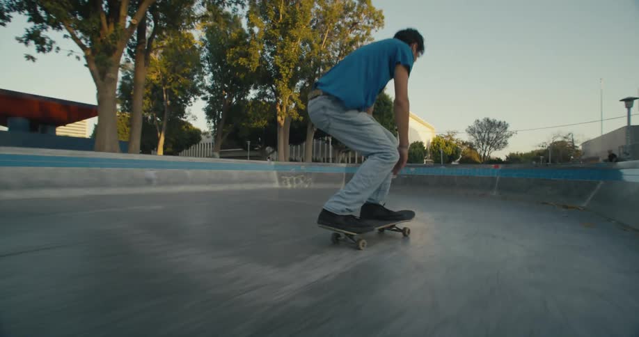 A man does jumps in the skatepark on his skateboard