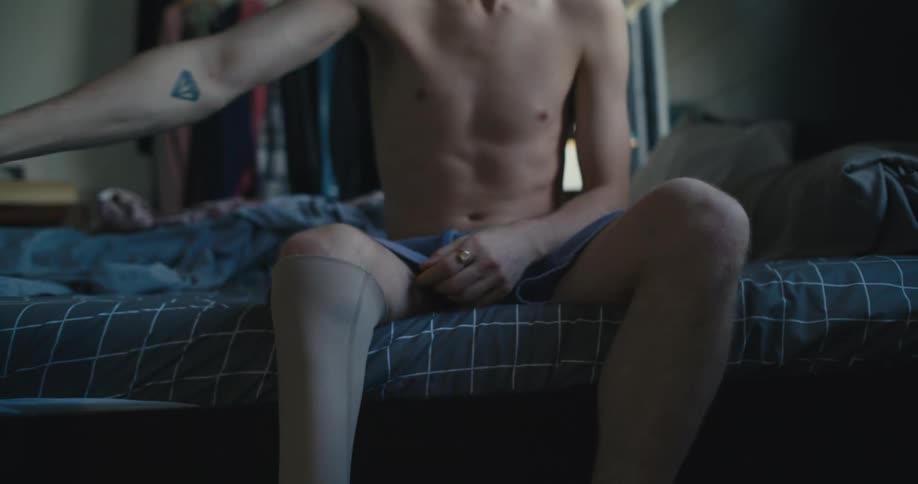 A man sits in bed and prepares to put his prosthetic leg on