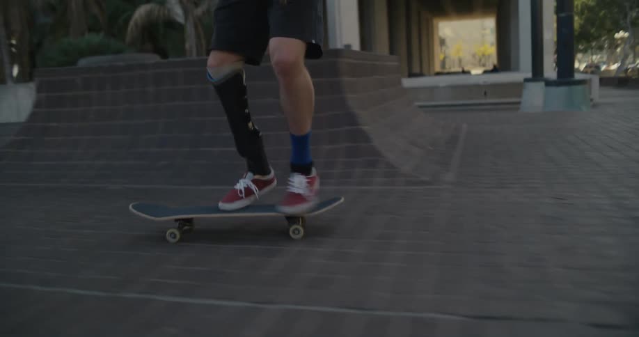 A males skateboards down a city sidewalk as people walk in the background