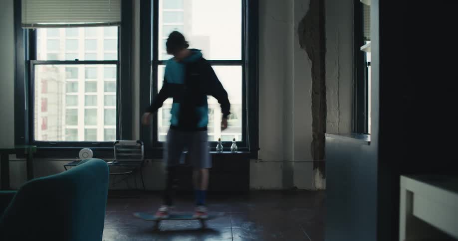 A man rides a skateboard in his high rise apartment