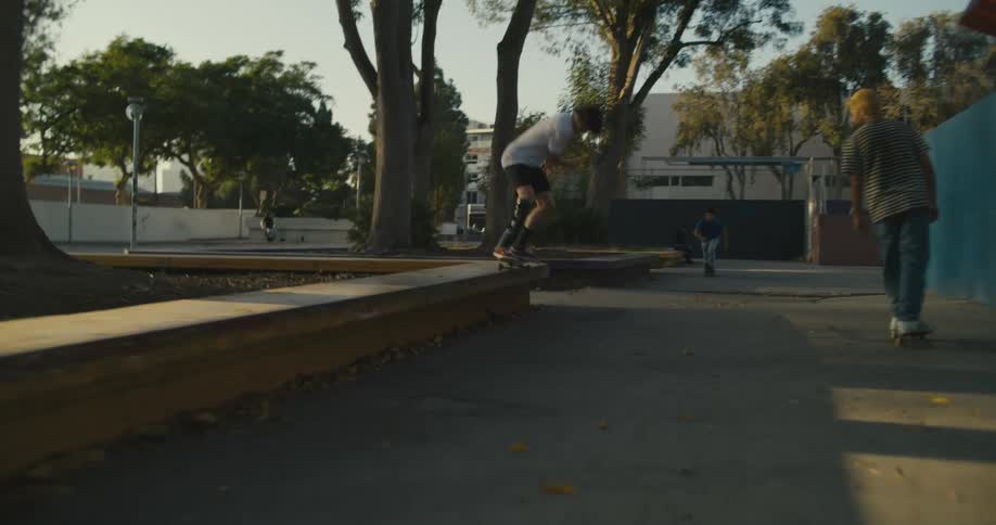 A group of skateboarders skate and perform tricks at a concrete park in the city