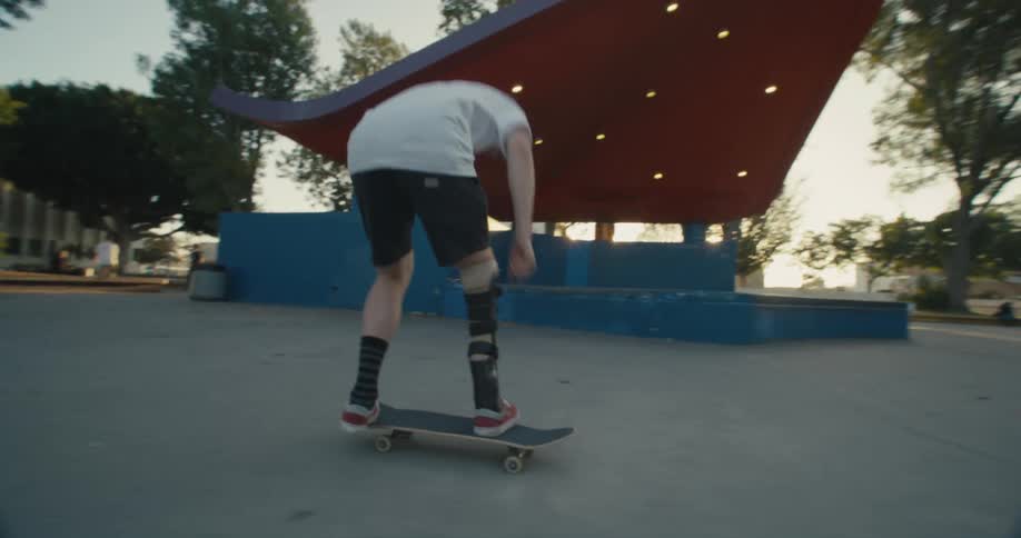 Skateboarding male with prosthetic flips skateboard during ride