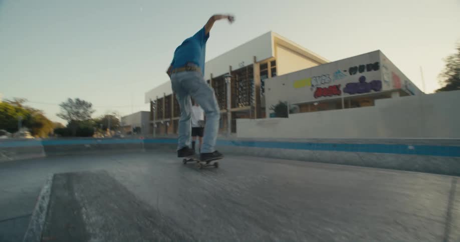 Skateboarder makes jump then jumps down on opposite end of platform in skate park