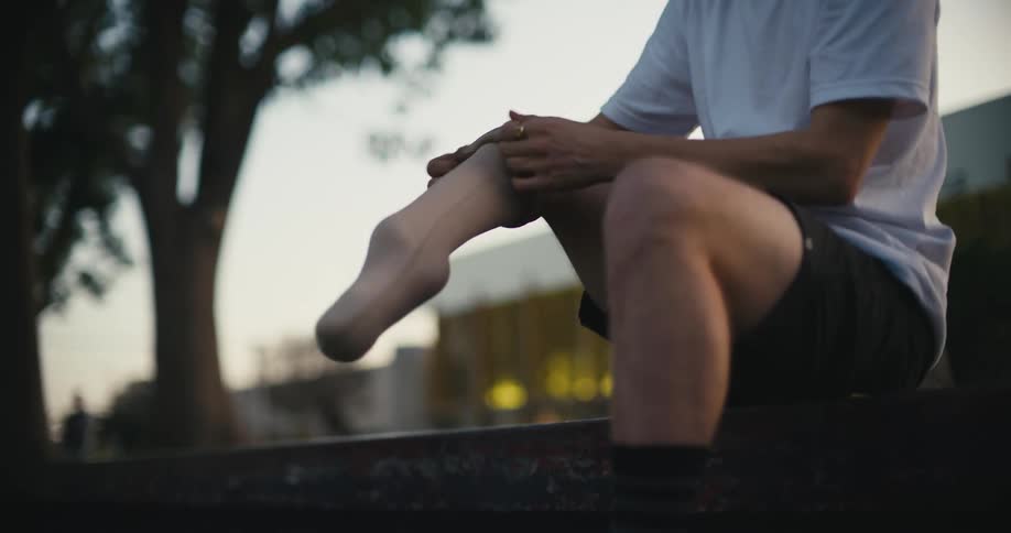 A man puts on his prosthetic leg while sitting in a park