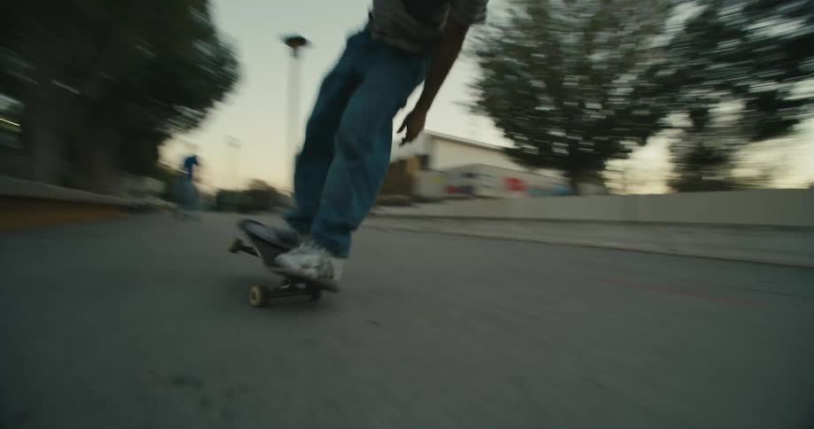 A young man skateboards over a set of steps toward other men waiting for him