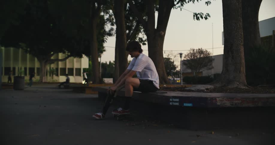 A man takes off his prosthetic leg while sitting at a park