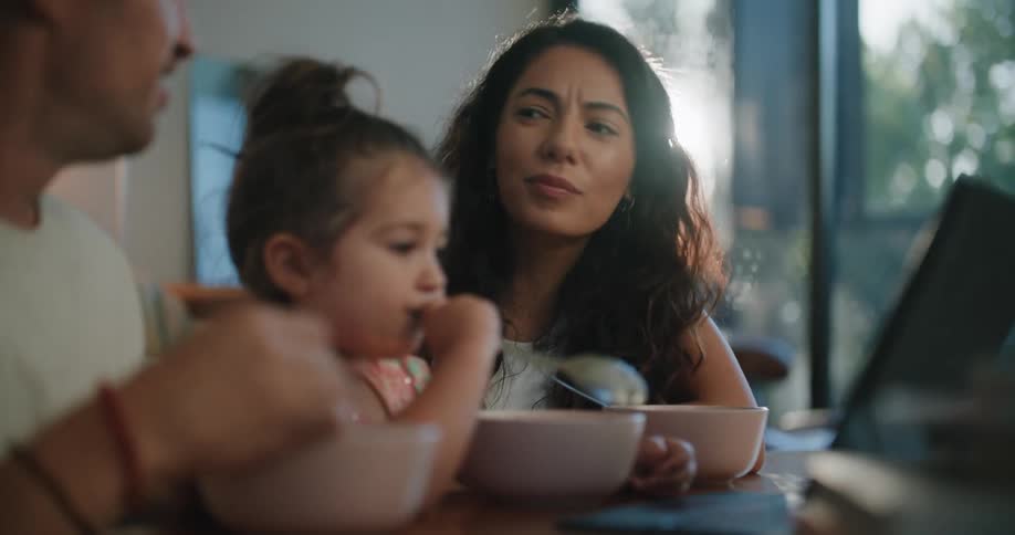 A family eats a meal while watching something on a laptop together