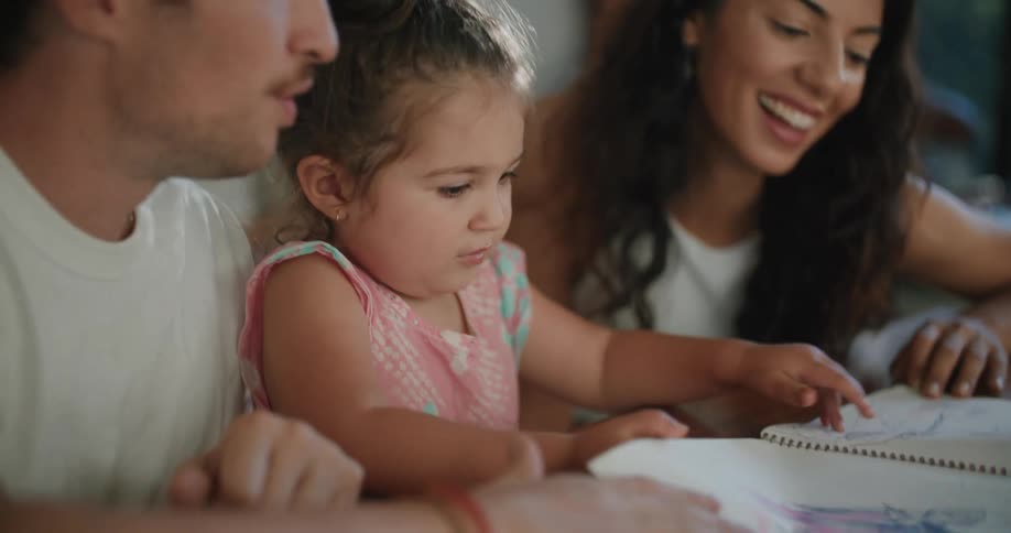 A mother and father looking at coloring in their kids book
