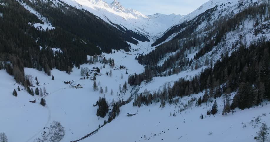 An aerial view of a snow covered valley in a mountain range