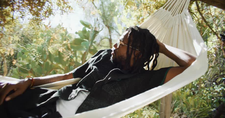 Man reclining in hammock sways back and forth