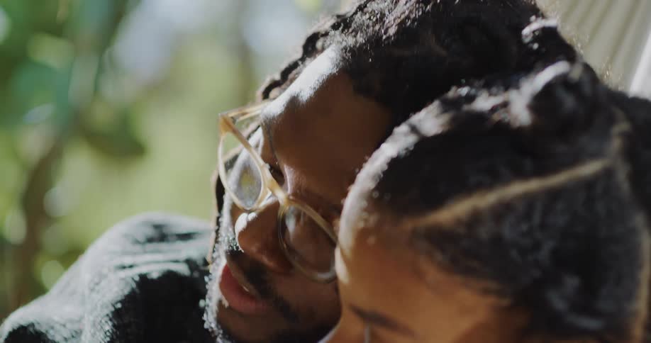 A man and woman cuddling while reading together on a sunny day