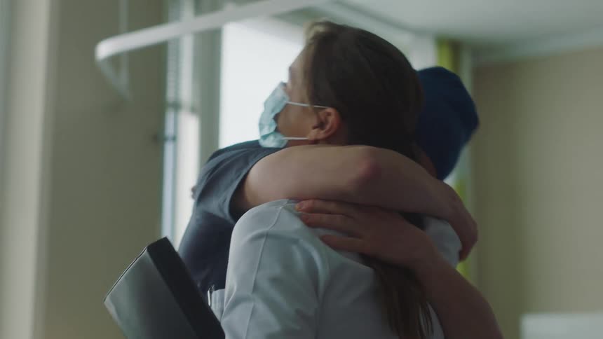 Hospital patient talks to visitor while lying in bed then stands and hugs doctor