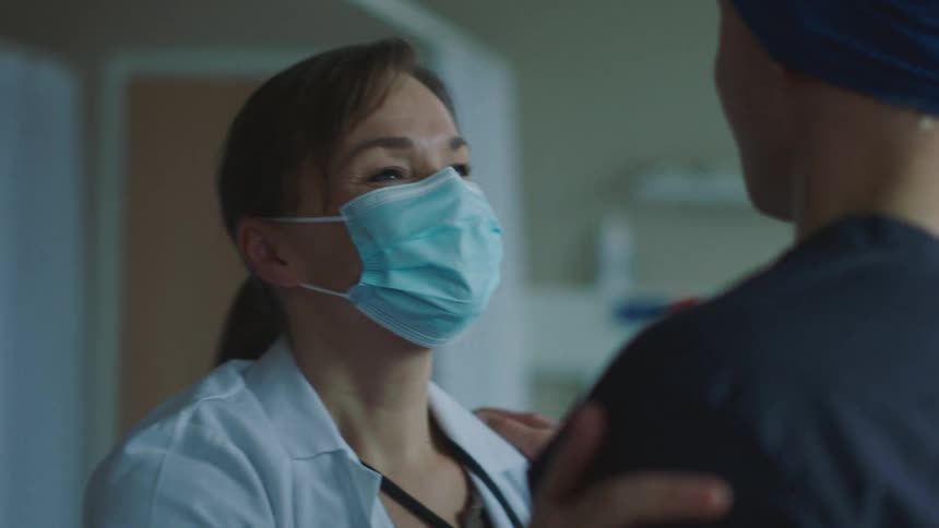 A man in a hospital hugs a doctor and they talk