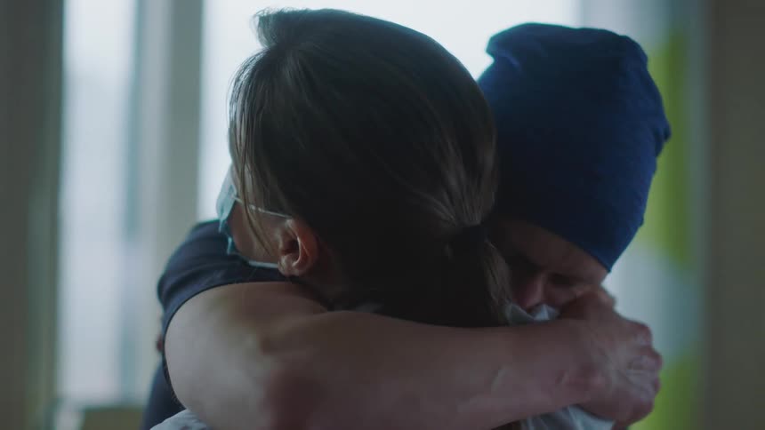 Patient stands up from a hospital bed to hug a doctor with relief