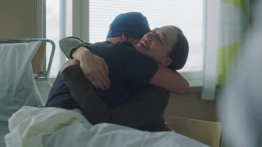 A hospital patient cheers and hugs his wife after speaking with a doctor