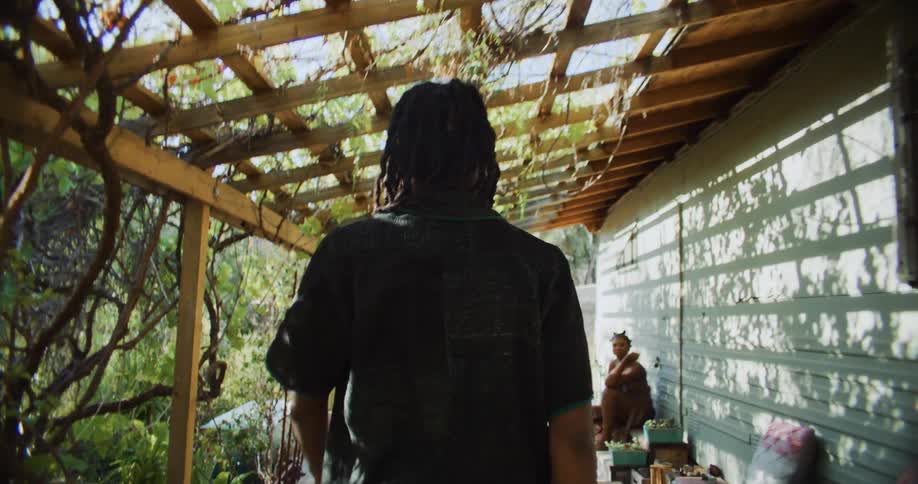 A man walks on to a porch where a woman sits