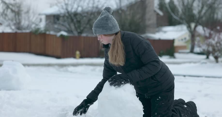 A girl is building a snowman