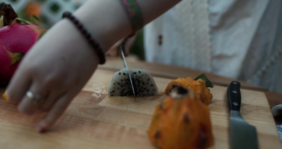 A woman is cutting dragon fruit